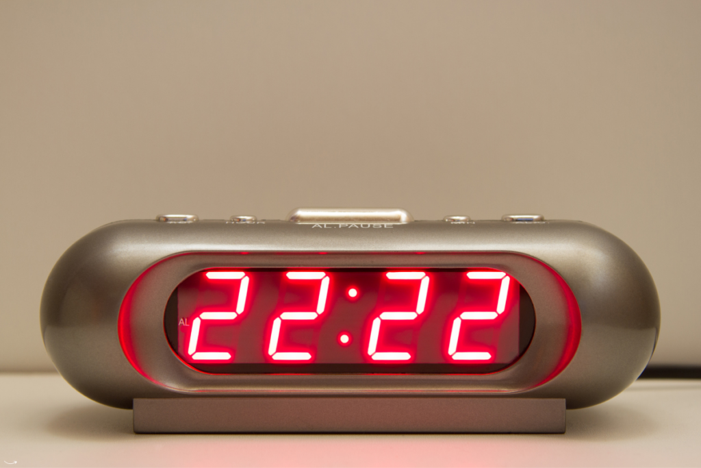 Een digitale wekker toont de tijd 22:22, een veelvoorkomend engelengetal, met een zachte gloed in de achtergrond.