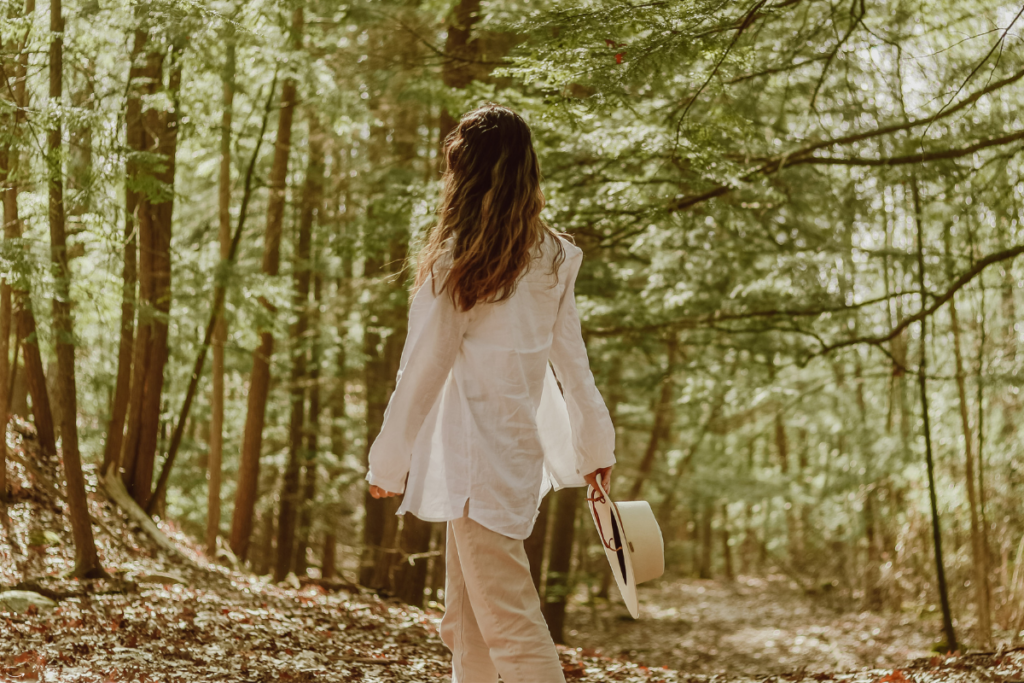 Vrouw die rustig in het bos wandelt, omringd door groen en natuur.